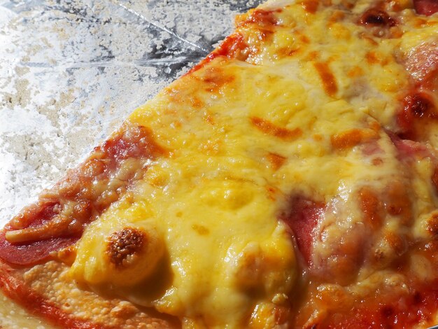 Pizza met tomaten en kaas in een kartonnen doos en aluminiumfolie heerlijke pizza close-up koerier