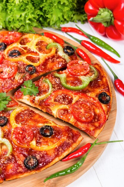 Pizza met tomaten, paprika en olijven op een houten ondergrond