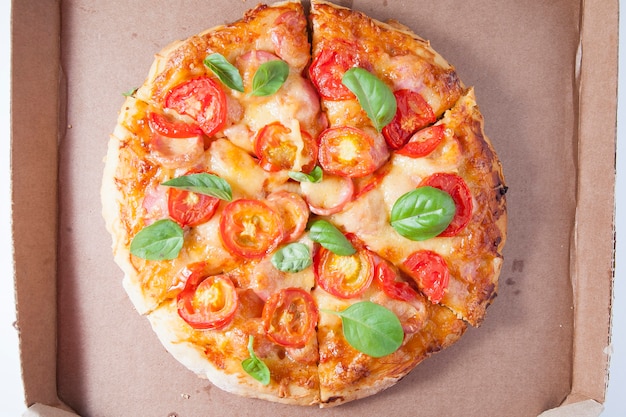 Pizza met tomaten, worstjes en kaas in een kartonnen doos