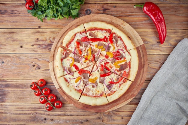 Pizza met vlees, groenten en champignons, houten achtergrond