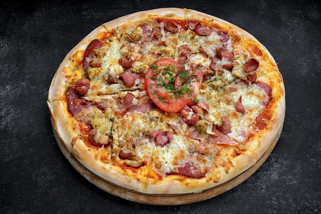 Pizza met vleesworst en kippenkaas en tomaten op een grijze betonnen ondergrond met selectieve focus