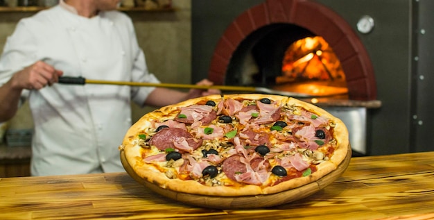 Pizza near the stone stove with fire Background of a traditional pizzeria restaurant with a fire place