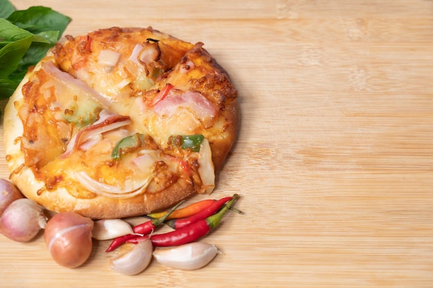 Фото Пицца на деревянной доске со свежим перцем и базиликом с чесноком на фоне копировального пространства