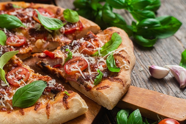 Pizza op een houten bord met basilicum en basilicum