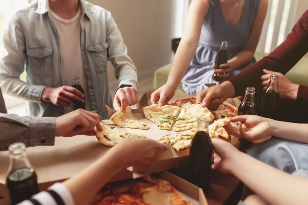 Pizza party group of friends chatting eating pizza drinking sweet soda water