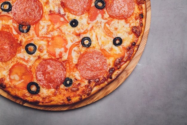 Пицца пепперони с моцареллой и орегано на черном фоне