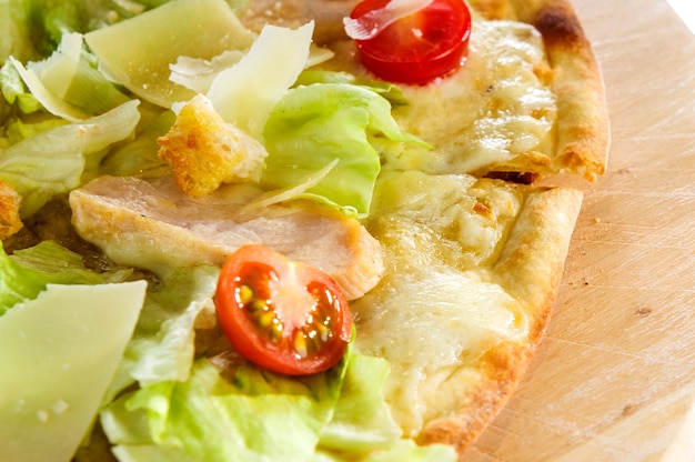 Pizza quattro fromaggi gegarneerd met verse salade op een houten bord.