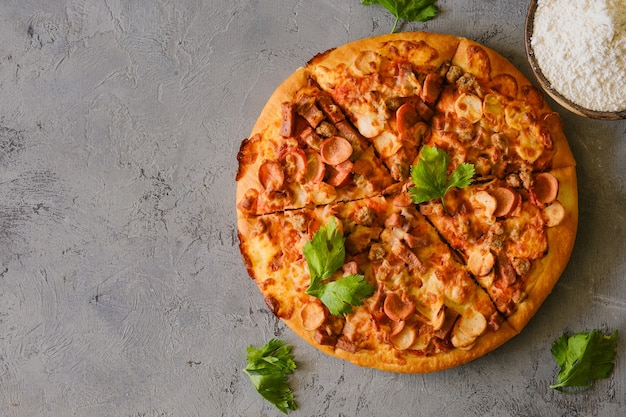 Pizza on rustic grey background, top view. Pizza with minced meat, celery and Mozzarella Cheese close up.