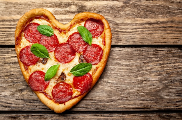 Pizza in the shape of a heart on a wooden table