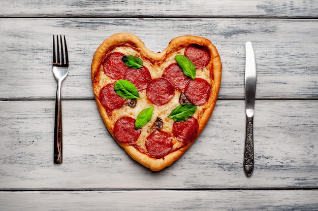 Pizza in the shape of a heart on a wooden table