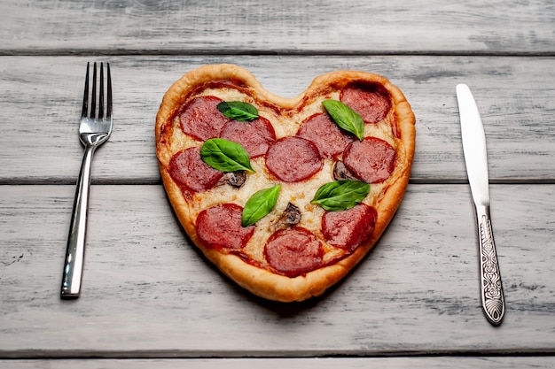 Pizza in the shape of a heart on a wooden table