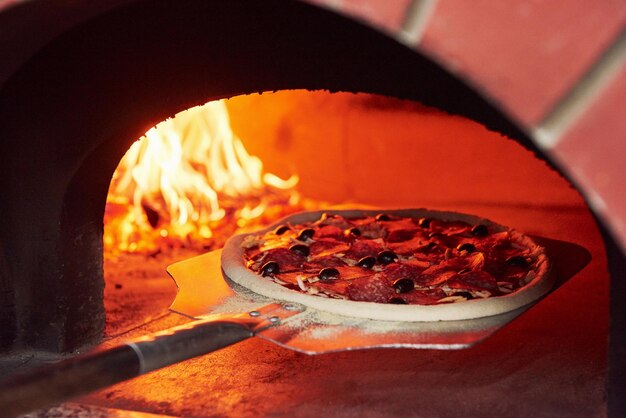 Photo pizza on the showel fire burning in the furnace close up view of wood in flames