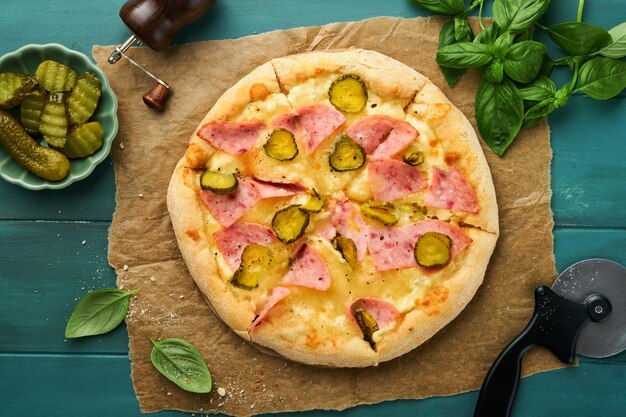 Pizza Traditional Bacon pizza with ham mushrooms pickled cucumber and cheese and cooking ingredients tomatoes basil on wooden table backgrounds Italian Traditional food Top view Mock up