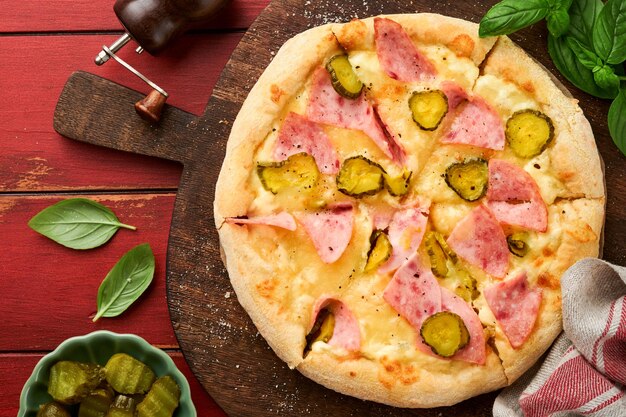 Pizza Traditional Bacon pizza with ham mushrooms pickled cucumber and cheese and cooking ingredients tomatoes basil on wooden table backgrounds Italian Traditional food Top view Mock up