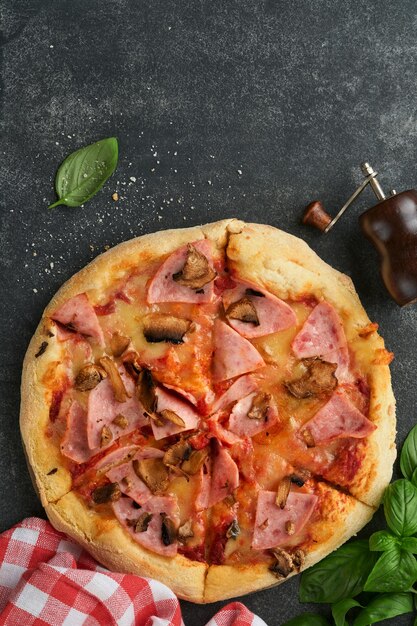 Пицца Традиционная пицца с беконом, ветчиной, грибами, маринованными огурцами, сыром и кулинарными ингредиентами, помидорами и базиликом на деревянном столе. Итальянская традиционная еда. Вид сверху. Макет.