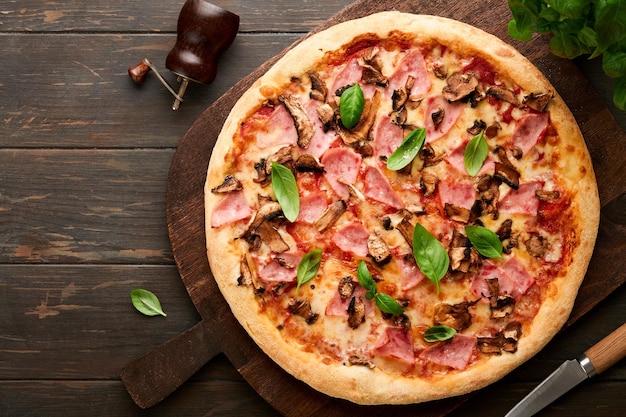 Pizza Traditional Bacon pizza with ham mushrooms pickled cucumber and cheese and cooking ingredients tomatoes basil on wooden table backgrounds Italian Traditional food Top view Mock up