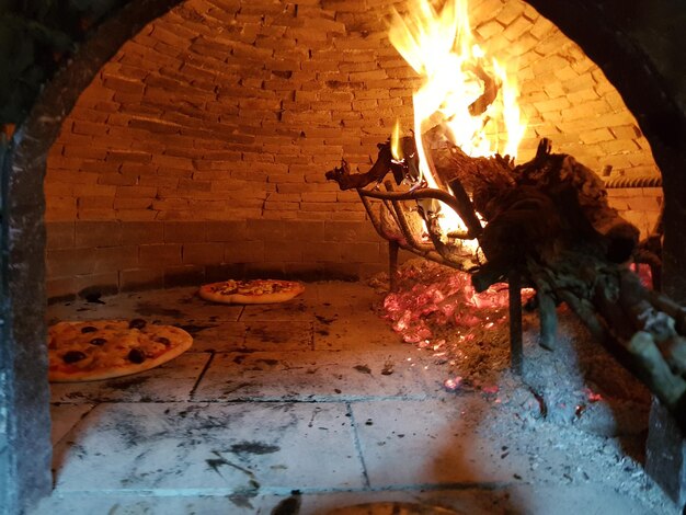 Photo pizza in traditional oven at night
