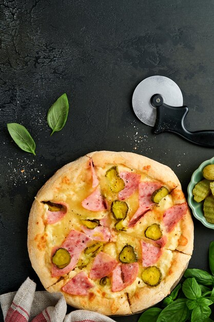 Foto pizza traditioneel bacon pizza met ham paddenstoelen ingelegde komkommer en kaas en kookingrediënten tomaten basilicum op houten tafel achtergrond italiaans traditioneel eten top view mock up