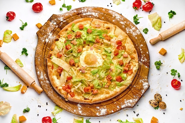 Foto pizza con carne di pancetta, tuorlo d'uovo e insalata verde sul piatto di legno