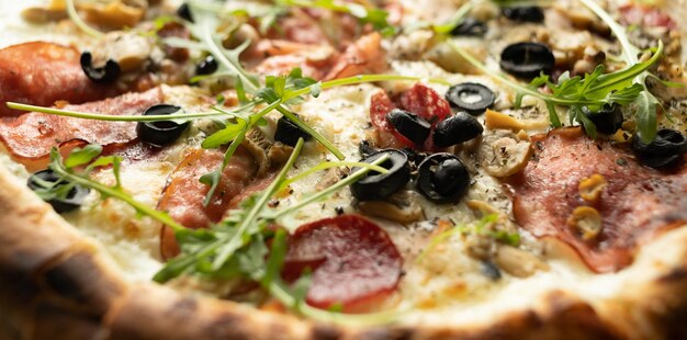 Pizza with cheese, salami and olives close-up. Ready-made pastries in a pizzeria.