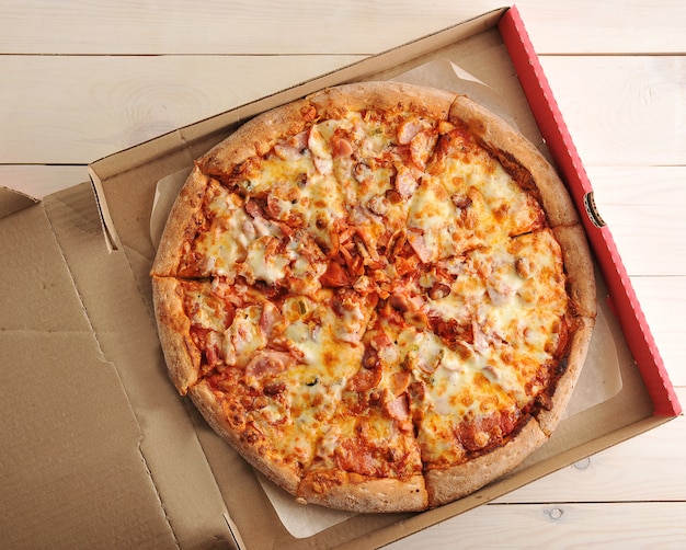 Pizza with cheese and spicy sausages in a cardboard box 