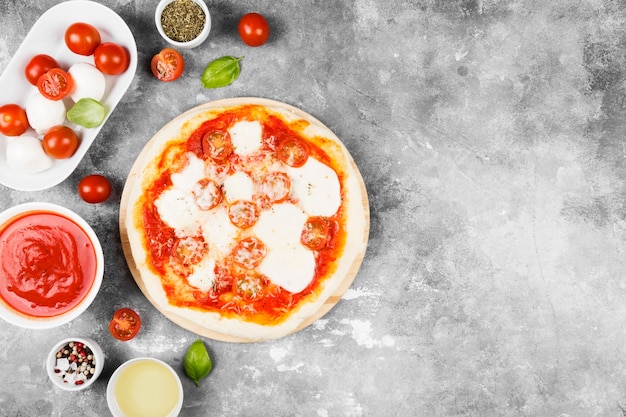 Пицца с сыром, помидорами и базиликом на сером пространстве. Вид сверху, скопируйте пространство. Пищевое пространство
