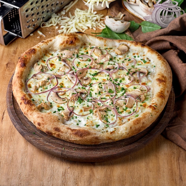 Pizza with chicken meat mushrooms cheese onion sauce on wooden background