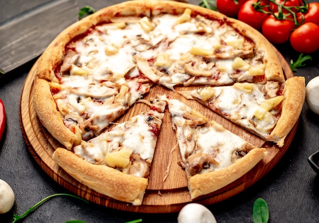 pizza with chicken mushrooms and pineapple on a stone background