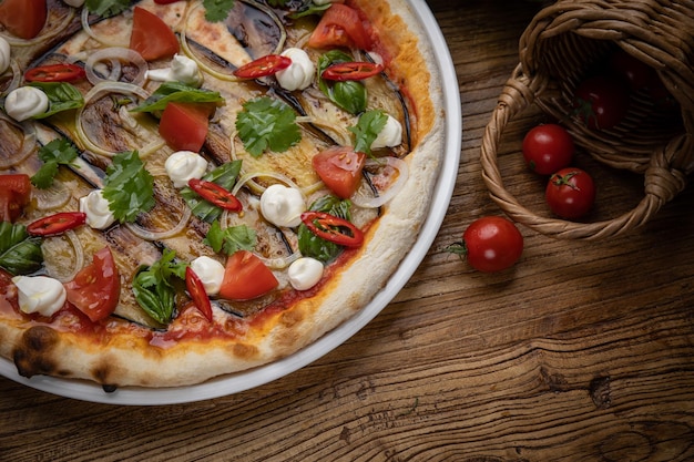 pizza with eggplant, cheese, tomatoes and chili peppers in a restaurant