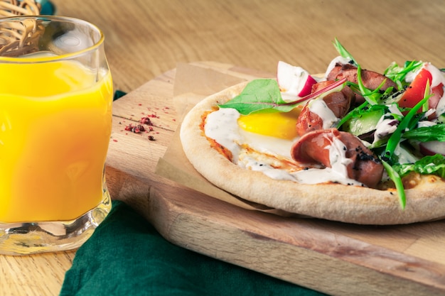 Pizza with eggs, sausages and herbs