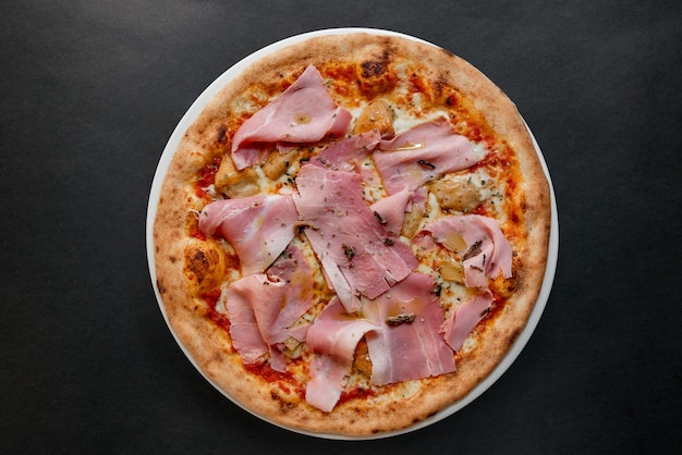 A pizza with ham on it on a plate