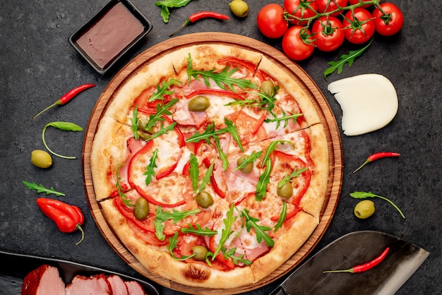 pizza with ham tomatoes cheese on a stone background