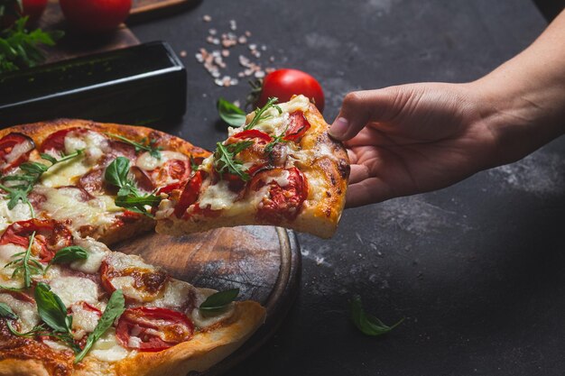 Pizza with hamtomatoes and mozzarella on a dark background