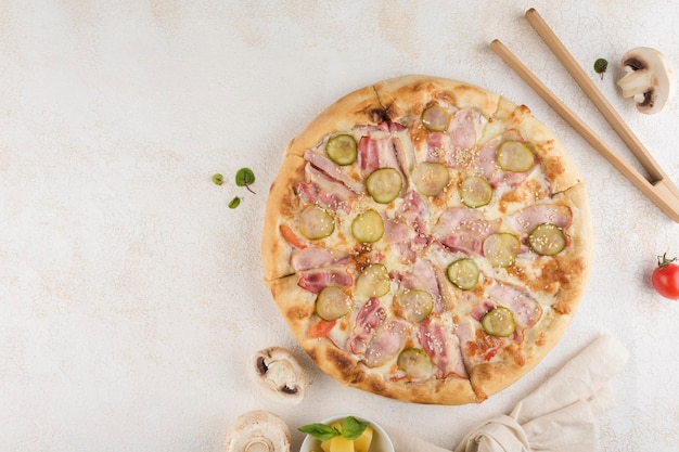 Pizza with hunting sausages, Mozzarella cheese, mushrooms, pickled cucumbers, tomatoes and mustard on a light background. Top view with a copy space for the text. Classic Italian food.