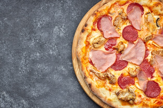 Pizza con carne, salsiccia, carne e funghi su uno sfondo grigio con posto per il testo. pizza 4 carni