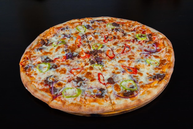 Pizza with meat and vegetables on a black background