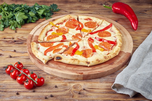 Pizza with meat, vegetables and mushrooms, wooden background