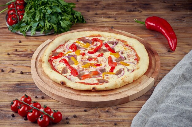 Pizza with meat, vegetables and mushrooms, wooden background