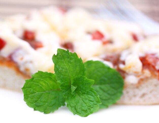 Pizza con foglie di menta da vicino su sfondo bianco