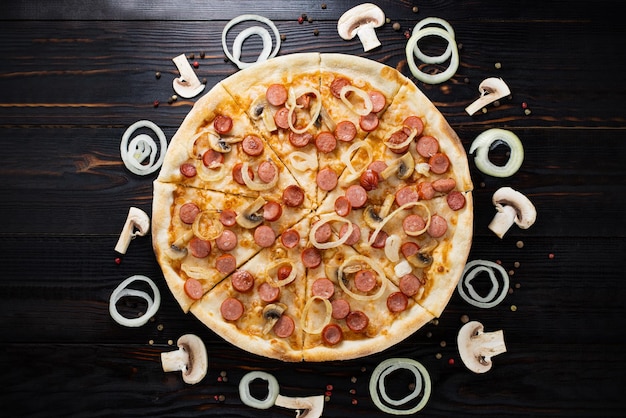 Foto pizza con funghi e cipolle caramellate su fondo di legno vista dall'alto