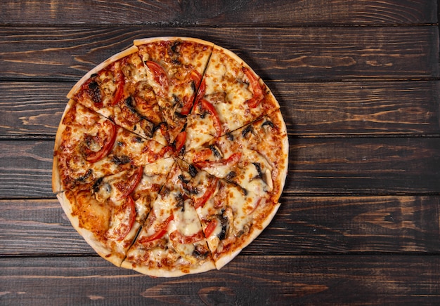 Photo pizza with mushrooms and chicken on a wooden table