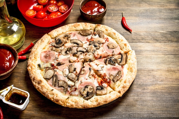 Pizza with mushrooms and ham. On a wooden table.