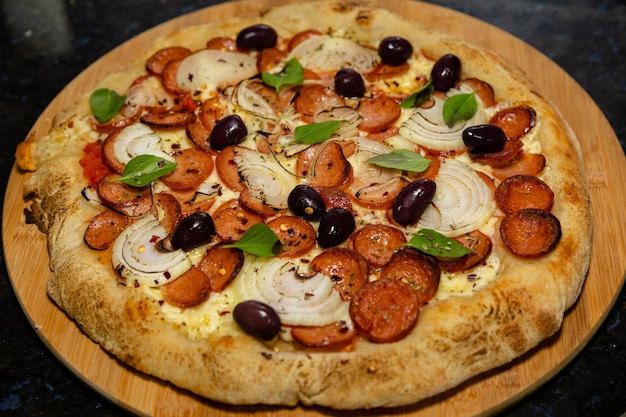 A pizza with olives, onions, and pepperoni on it