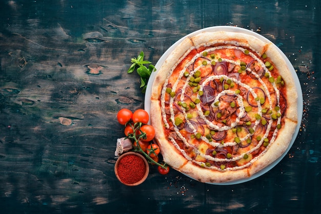 Pizza con cipolle salsiccia e cetriolo su uno sfondo di legno vista dall'alto spazio libero per il testo