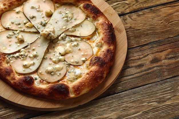 Pizza with pears and Gorgonzola cheese, italian pizza with pear and blue cheese on a wooden background.