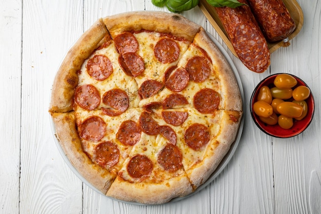 A pizza with pepperoni on it and a bowl of food next to it