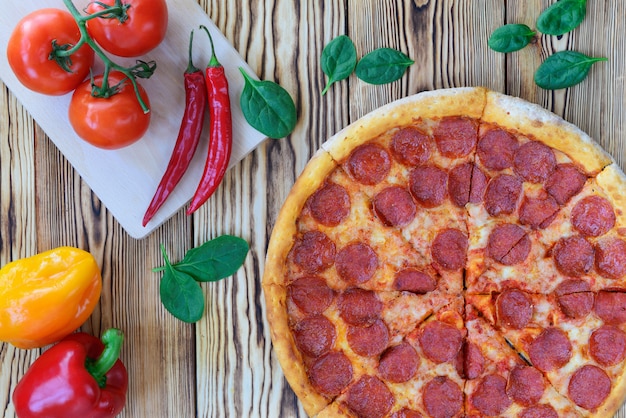 Pizza with pepperoni sausage on a wooden table.