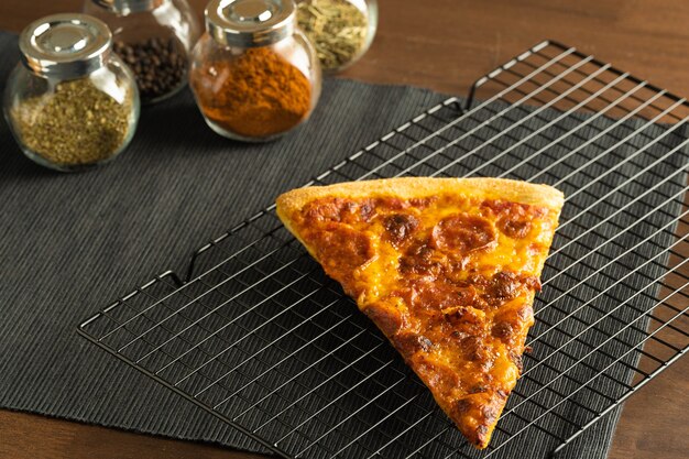 A pizza with pepperoni topping on a cooling rack place on black cloth placemat