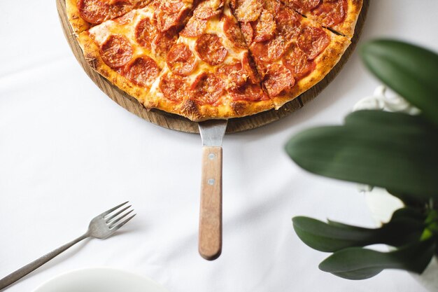 A pizza with pepperoni on a wooden serving tray.