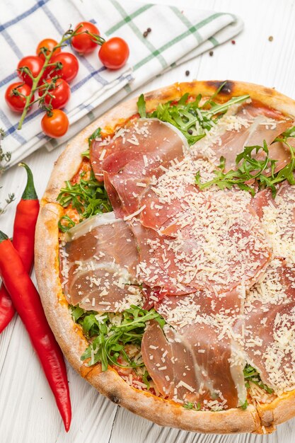 Pizza with prosciutto, arugula, tomatoes and parmesan